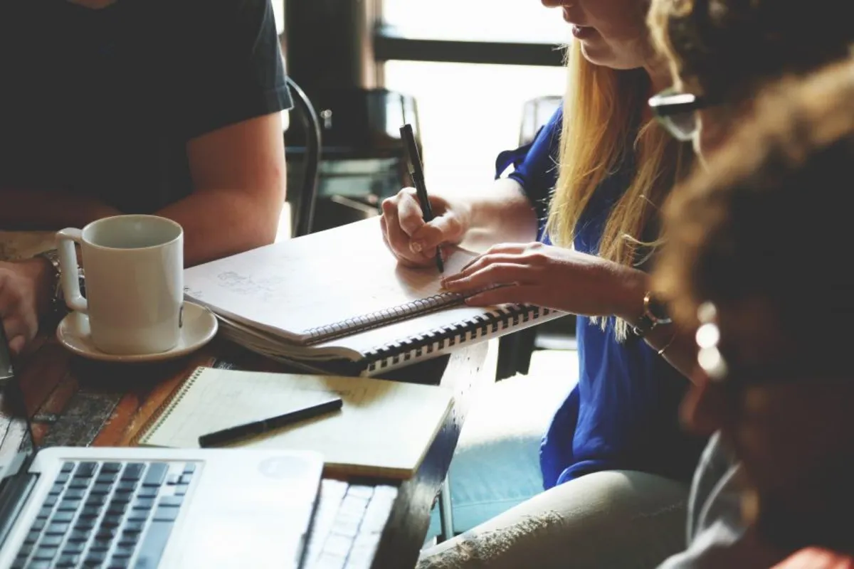 A small team working together around a table with notebooks and laptops